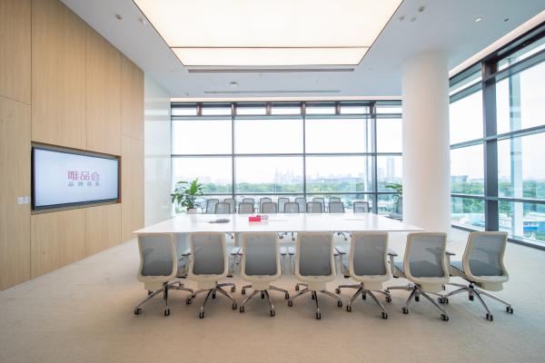 会议室办公家具工程实拍，白色长会议桌搭配灰白色会议椅，墙面设置显示屏，适用于商务会议、客户接待和项目汇报